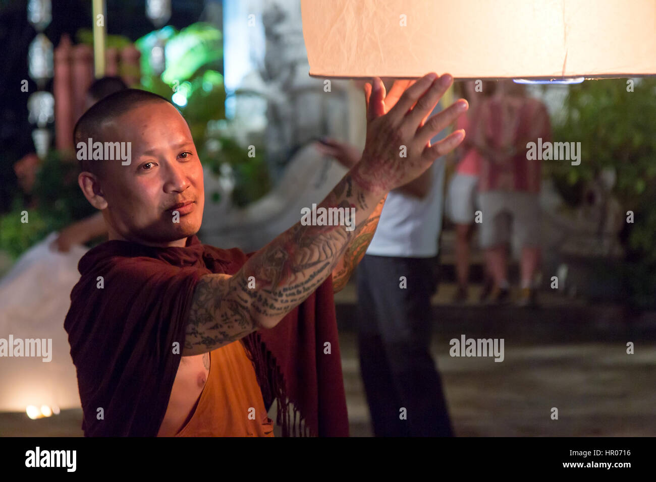 Buddhistischer Mönch hält eine traditionelle schwimmende Laterne mit einer Kerze in der Nacht. Nacht Feier in einem buddhistischen Tempel, Chiang Mai, Thailand Stockfoto