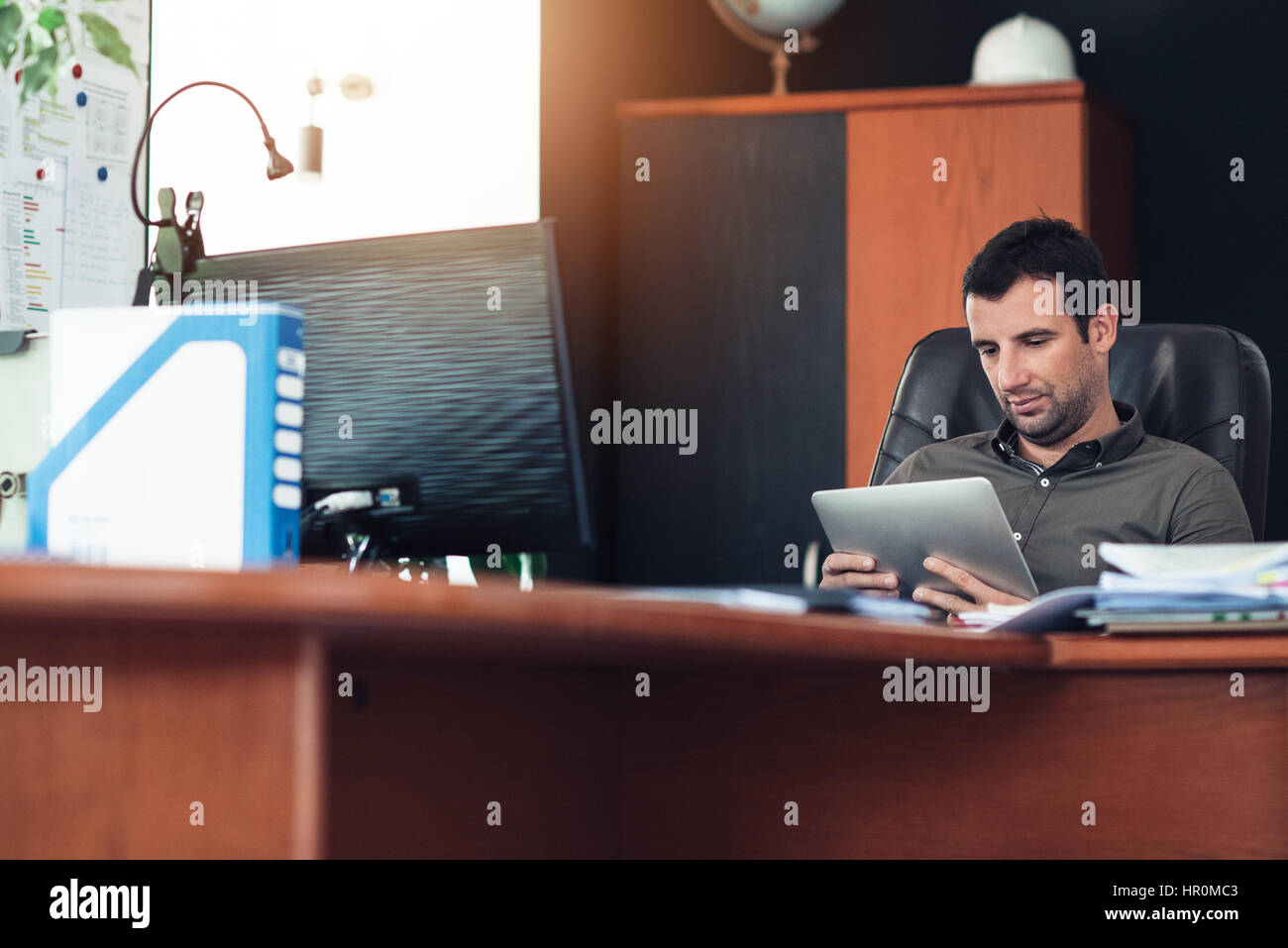 Selbstbewusst und erfolgreich Jungunternehmer mit einem digitalen Tablet beim Sitzen am Schreibtisch im Büro Stockfoto