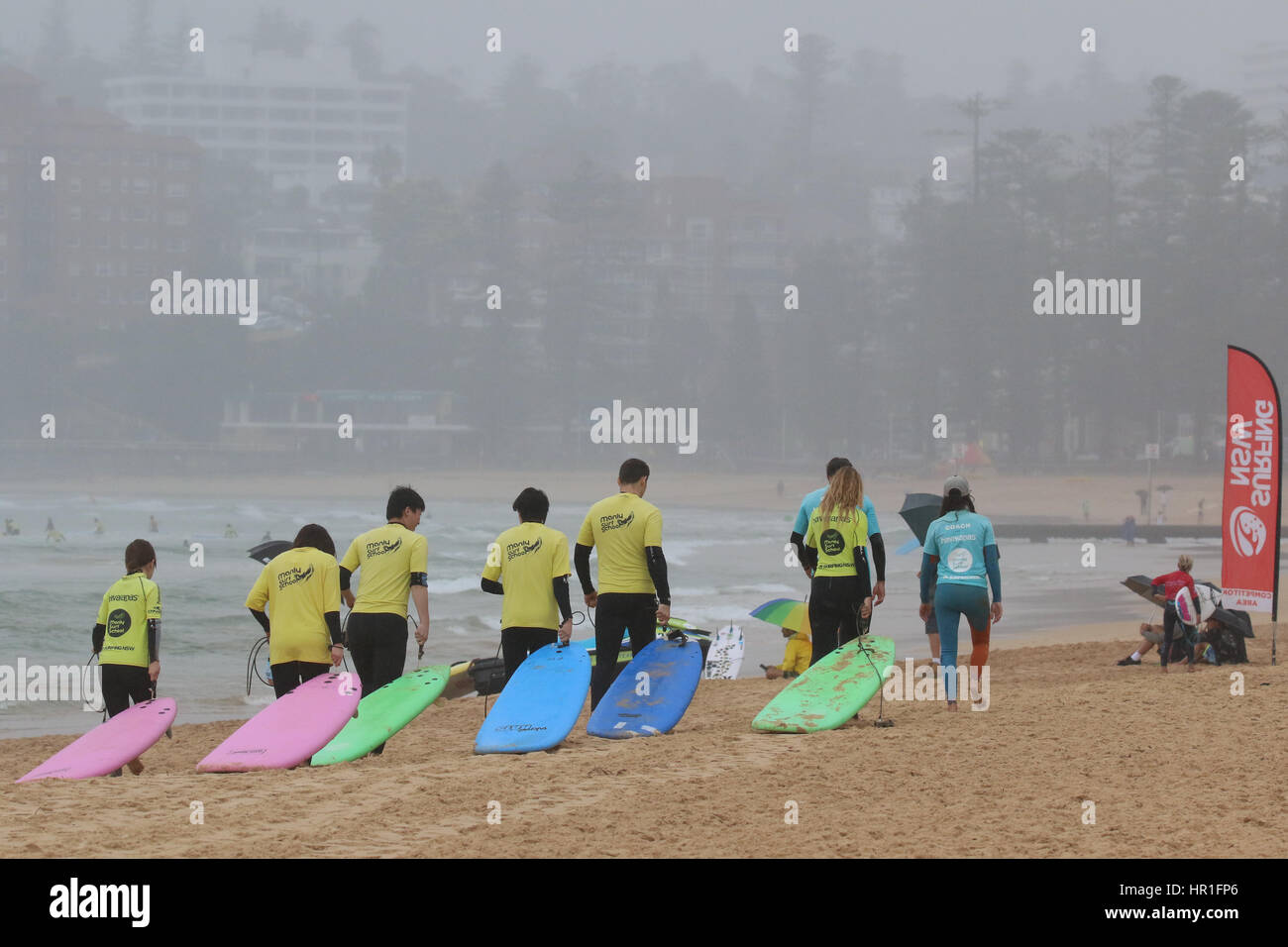 Manly Surf School Surfer ziehen Sie ihre Bretter entlang Manly Beach in Sydney, Australien vor dem Start der ihren Surfkurs. Stockfoto