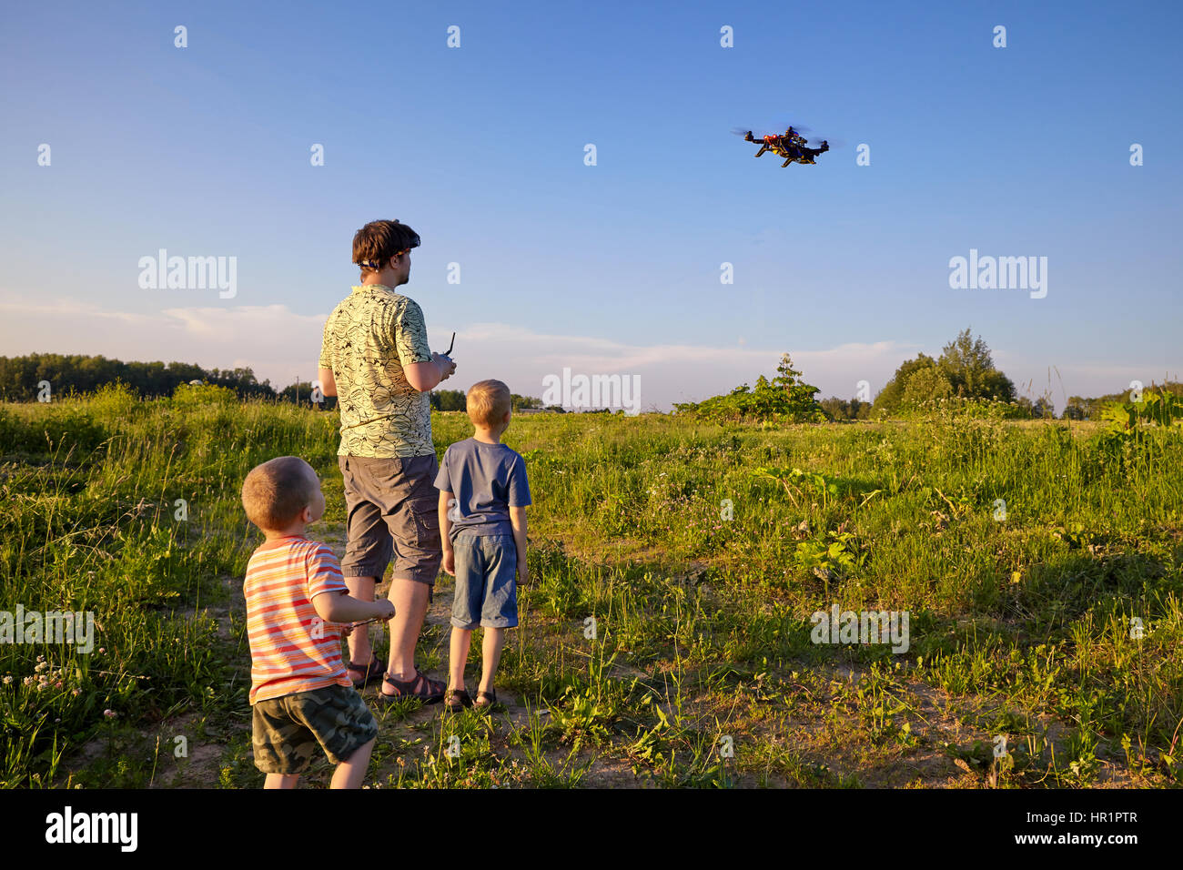 Vater und Sohn Steuerelemente RC Drone Quadrocopter in den Himmel Stockfoto