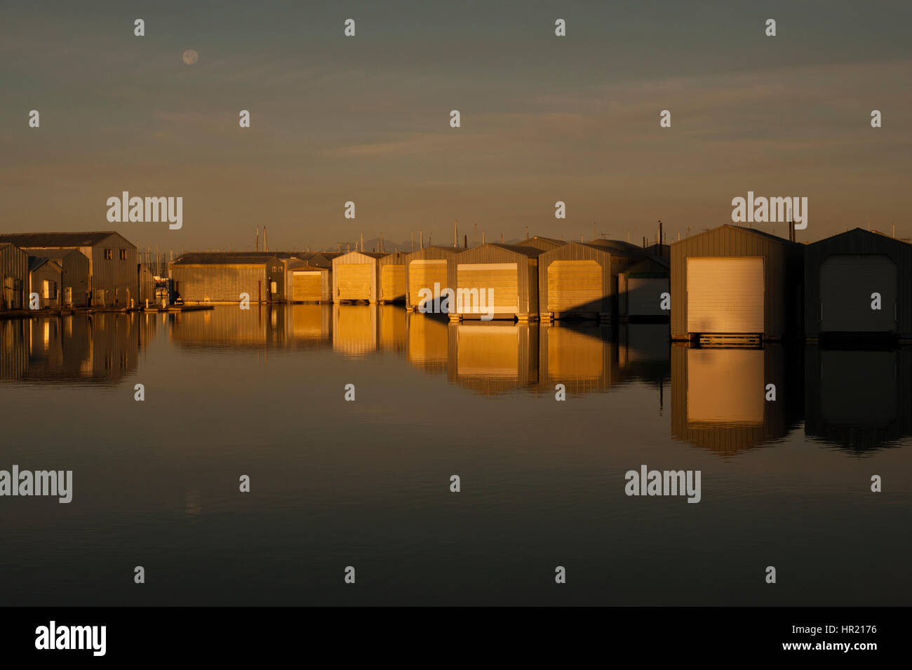 Bootshaus Reflexionen in Reihen entlang der Uferpromenade am Everett Marina mit mondaufgang. Stockfoto