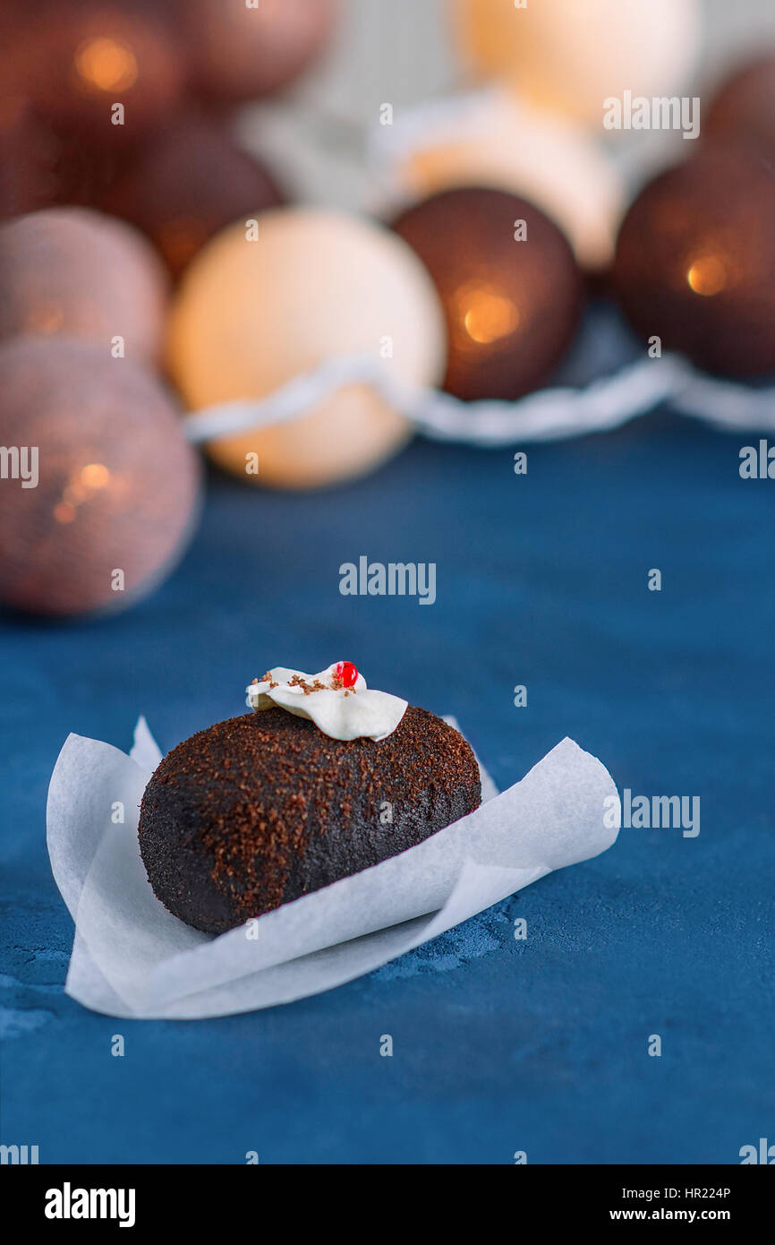 Süße Schokolade Kuchen auf einem schönen blauen Hintergrund. Spitze verziert mit weißen Creme, rot Stück Gelee, Schokolade-Chip. Im Hintergrund Schein Runde Stockfoto