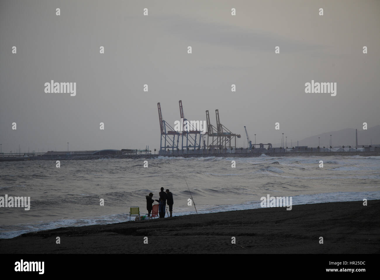 Vier Fischer auf an Land mit einer Rute. Malaga Hafen im Hintergrund. Stockfoto