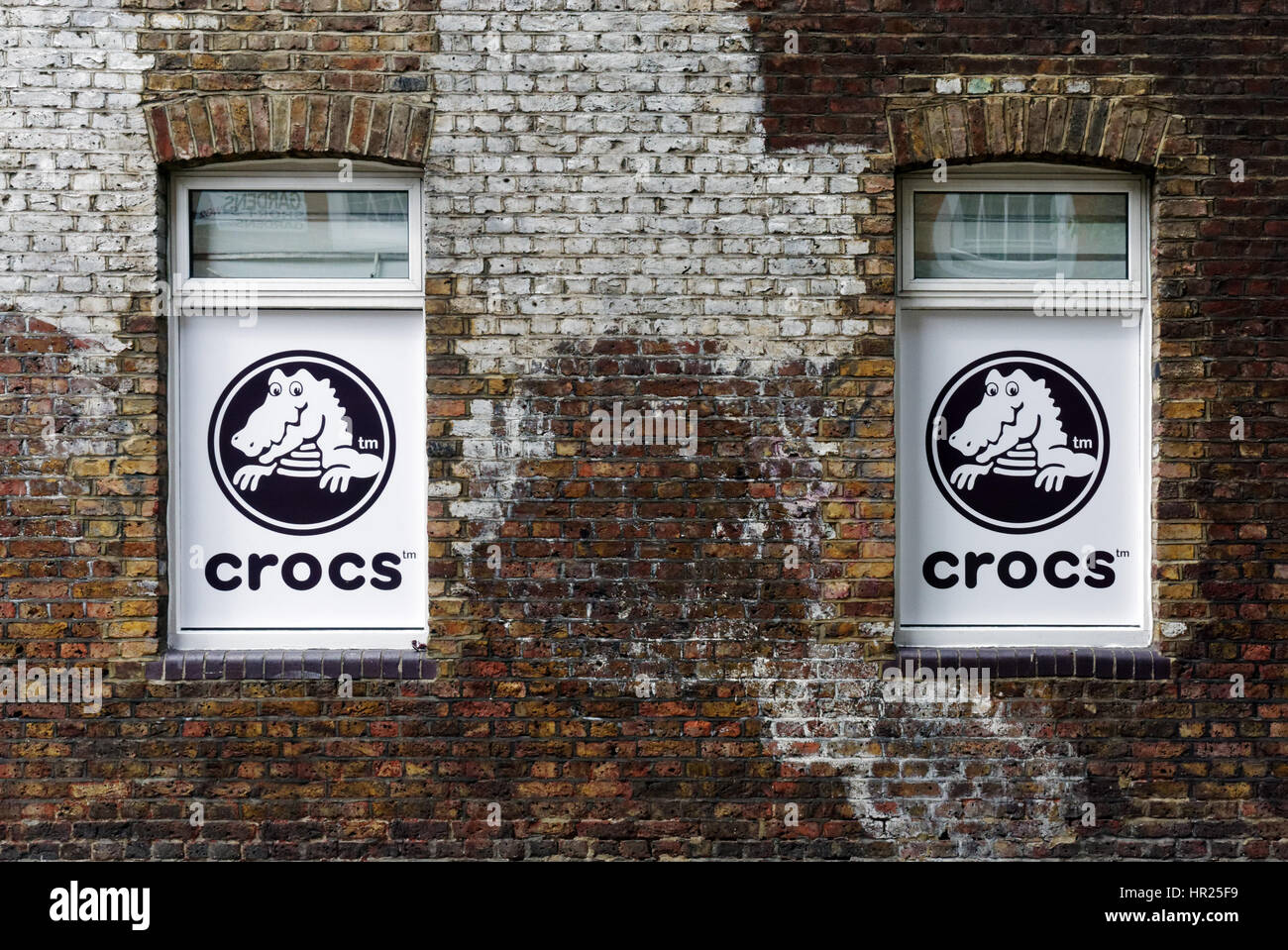 Zwei Fenster in einem Londoner Gebäude mit einer Anzeige für Crocs Schuhe Stockfoto