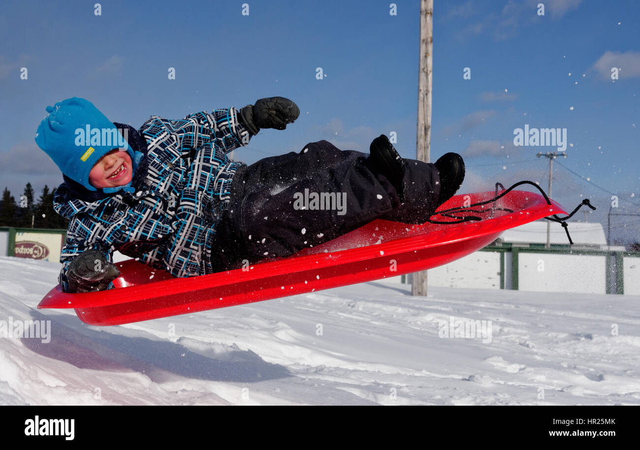 Ein kleiner Junge (4 Jahre alt) in die Luft sprang auf einem Schlitten in Quebec winter Stockfoto