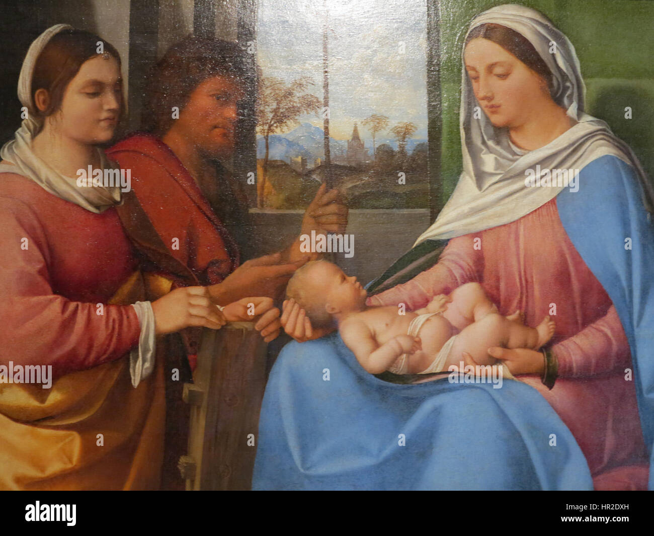 Dieses Kunstwerk, das Sebastiano del Piombo zugeschrieben wird, zeigt die Madonna mit Kind, flankiert von der Heiligen Katharina von Alexandria und Johannes dem Täufer. Das Gemälde ist eine Renaissance-Darstellung der Heiligen Familie, typisch für die religiöse Kunst dieser Zeit. Stockfoto