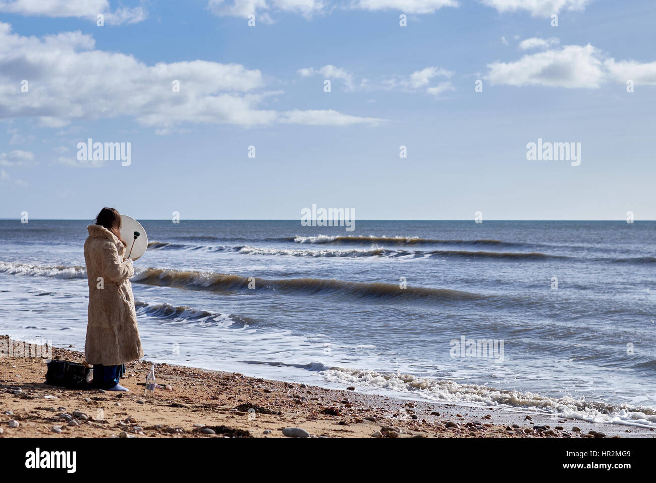 Eine Frau spielt eine irische Bodhrán-Trommel mit Blick auf das Meer in Charmouth in Dorset. GROSSBRITANNIEN Stockfoto