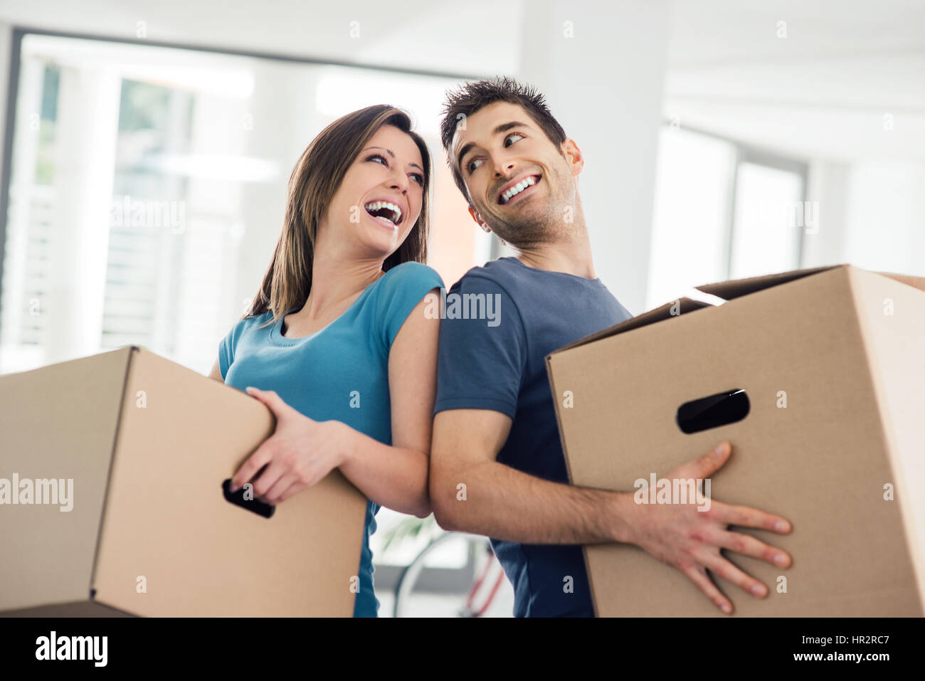 Glückliches Paar einander Augen anstarrte und tragen in ihrem neuen Haus-Boxen Stockfoto