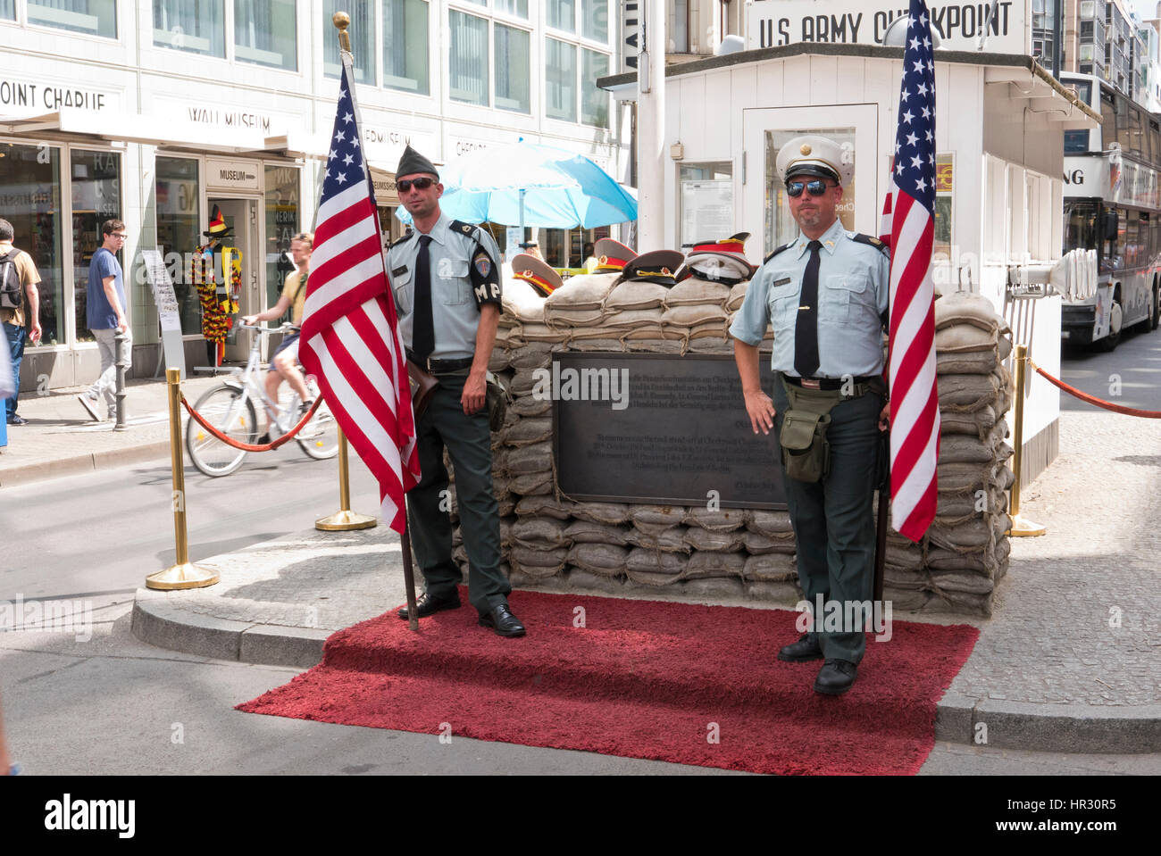 Zwei uniformierte halten amerikanische Flaggen am CheckPoint Charlie, Berlin, Deutschland Stockfoto