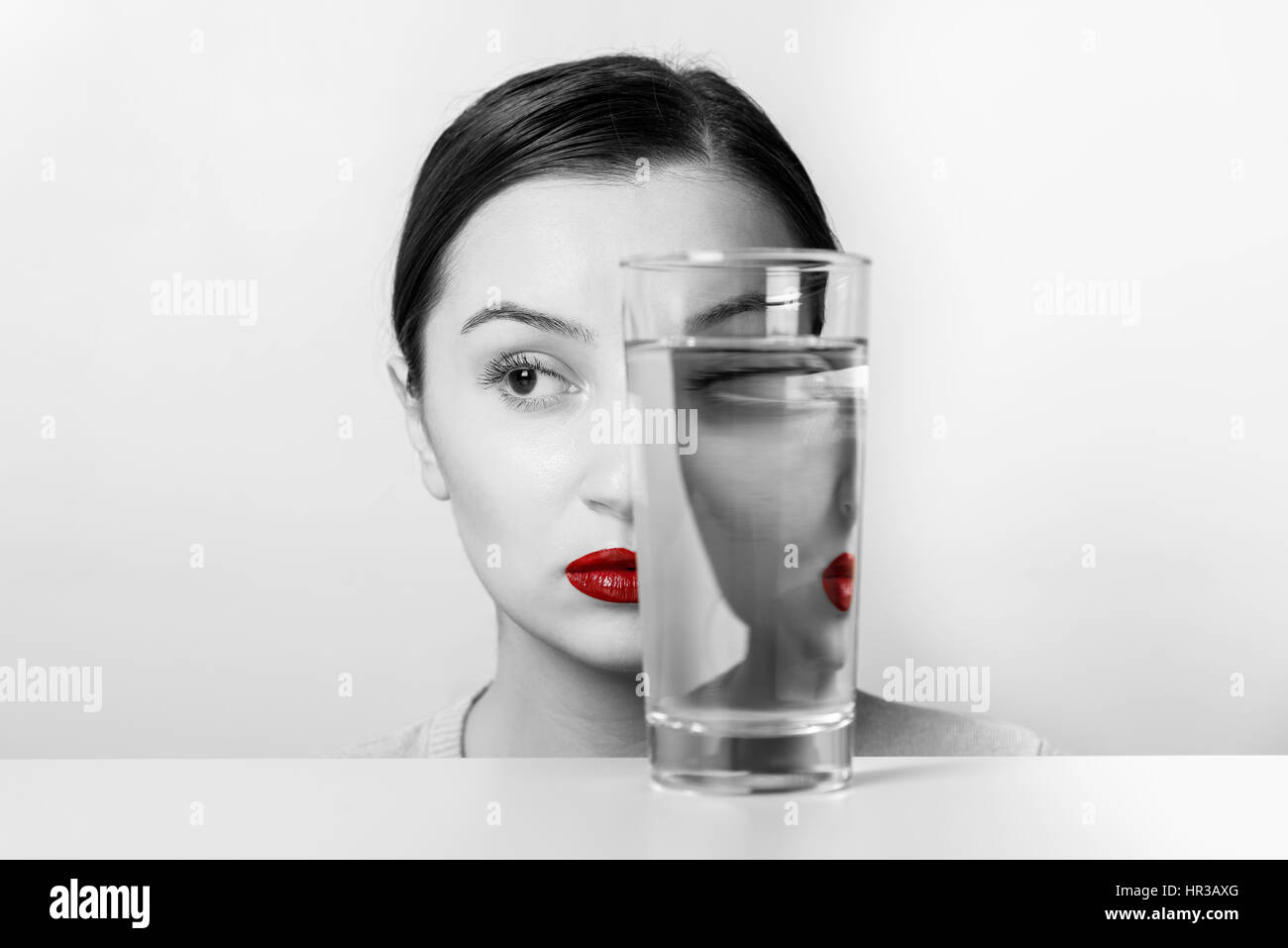 Frau Gesicht Verzerrungen im Glas Wasser Stockfoto