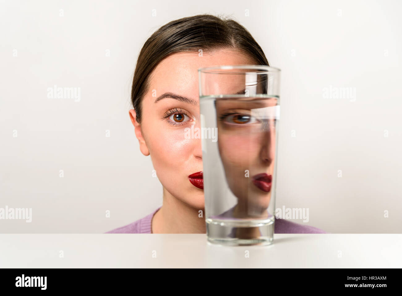 Frau Gesicht Verzerrungen im Glas Wasser Stockfoto