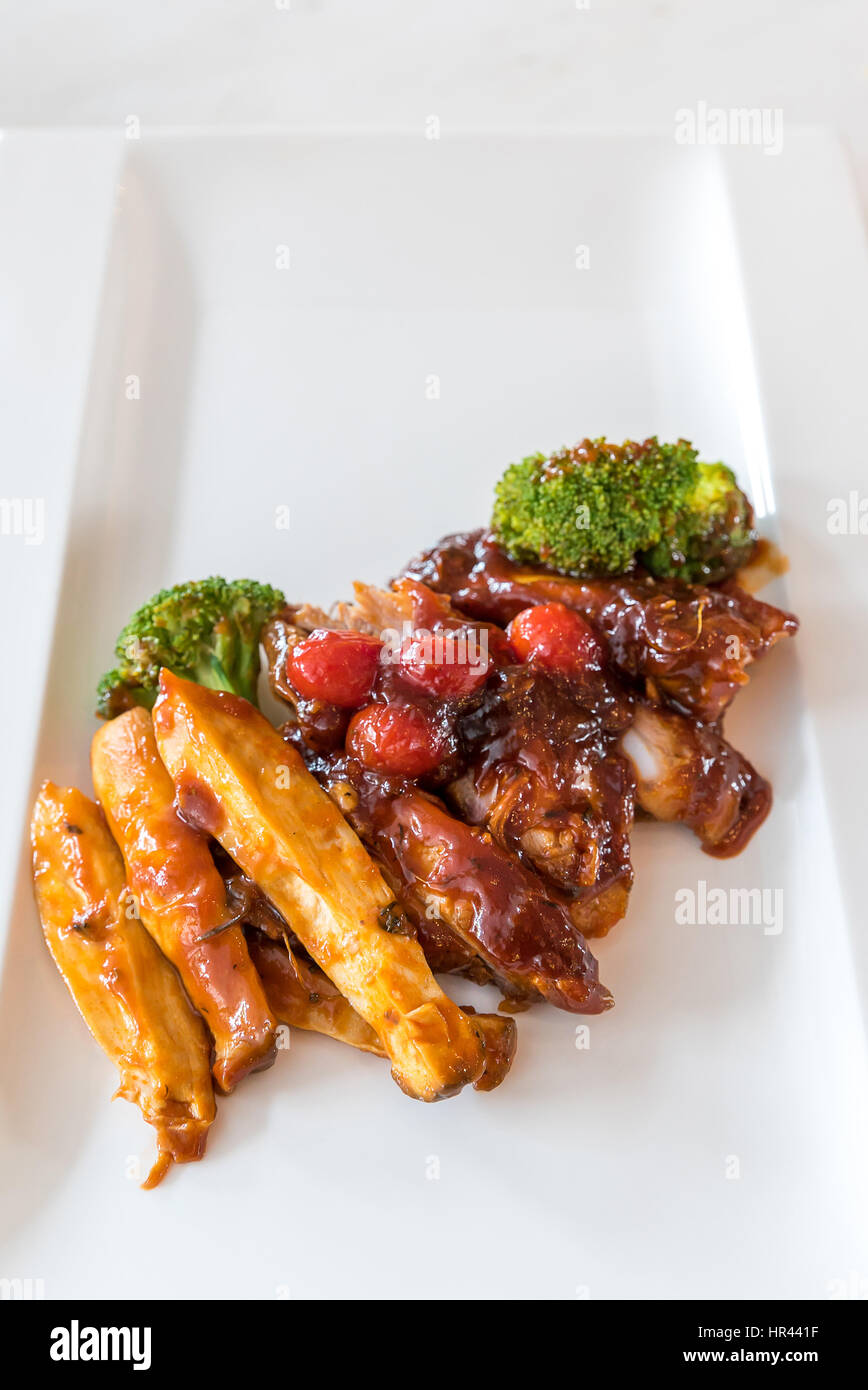 Schweinefleisch Rippe gegrillte und gebratene Kartoffelspalten auf weißen Teller mit Sauce und Gemüse, Gourmet-Küche. Stockfoto