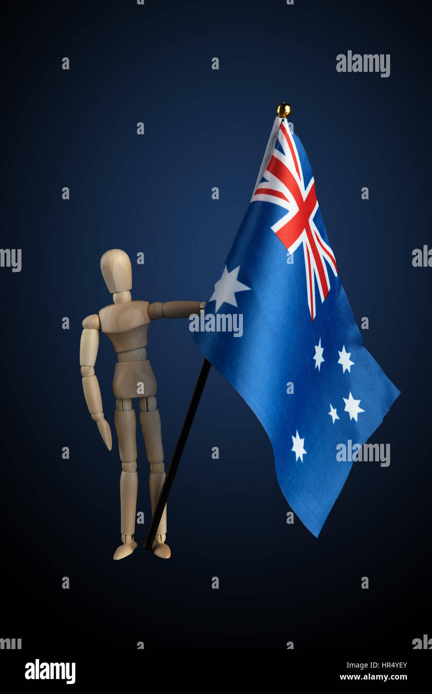 Holz Figur hält australische Fahne auf dunklem Hintergrund mit blauer Scheinwerfer Stockfoto