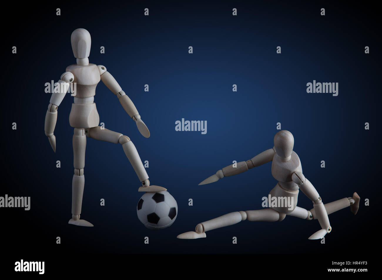 Zwei Holzfiguren spielen Fußball-Konzept auf dunklem Hintergrund mit blauer Scheinwerfer Stockfoto