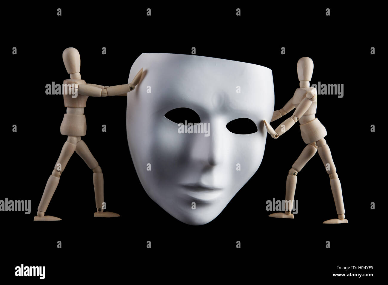 Zwei Holzfiguren hält eine weiße menschliches Gesichtsmaske auf schwarzem Hintergrund isoliert. Anonymität und Gesichtslosigkeit Konzept Stockfoto