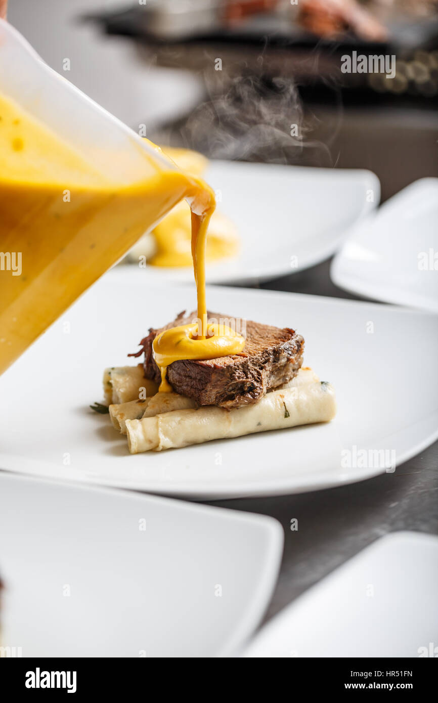 Koch Gießen gamy Soße auf das Essen bereitet seinen Teller zum Mittagessen Stockfoto