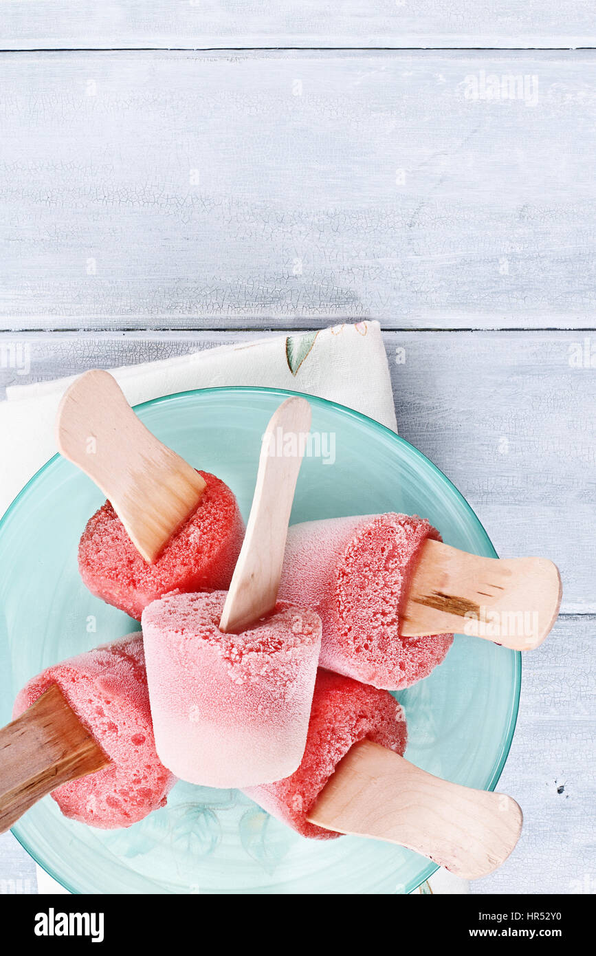 Erdbeer Eis am Stiel über eine hölzerne Tischplatte aus Erdbeeren und Joghurt hergestellt. Erschossen von oben. Stockfoto