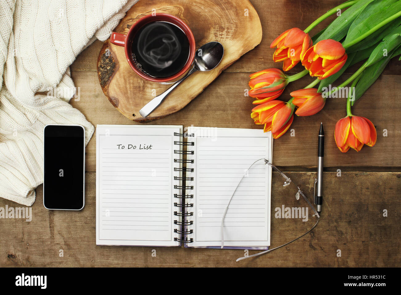 Aufwand für ein offenes Buch, Handy, Kaffee und Blumen über eine hölzerne Tischplatte bereit, eine Agenda zu planen. Flache Laien Draufsicht Stil. Stockfoto
