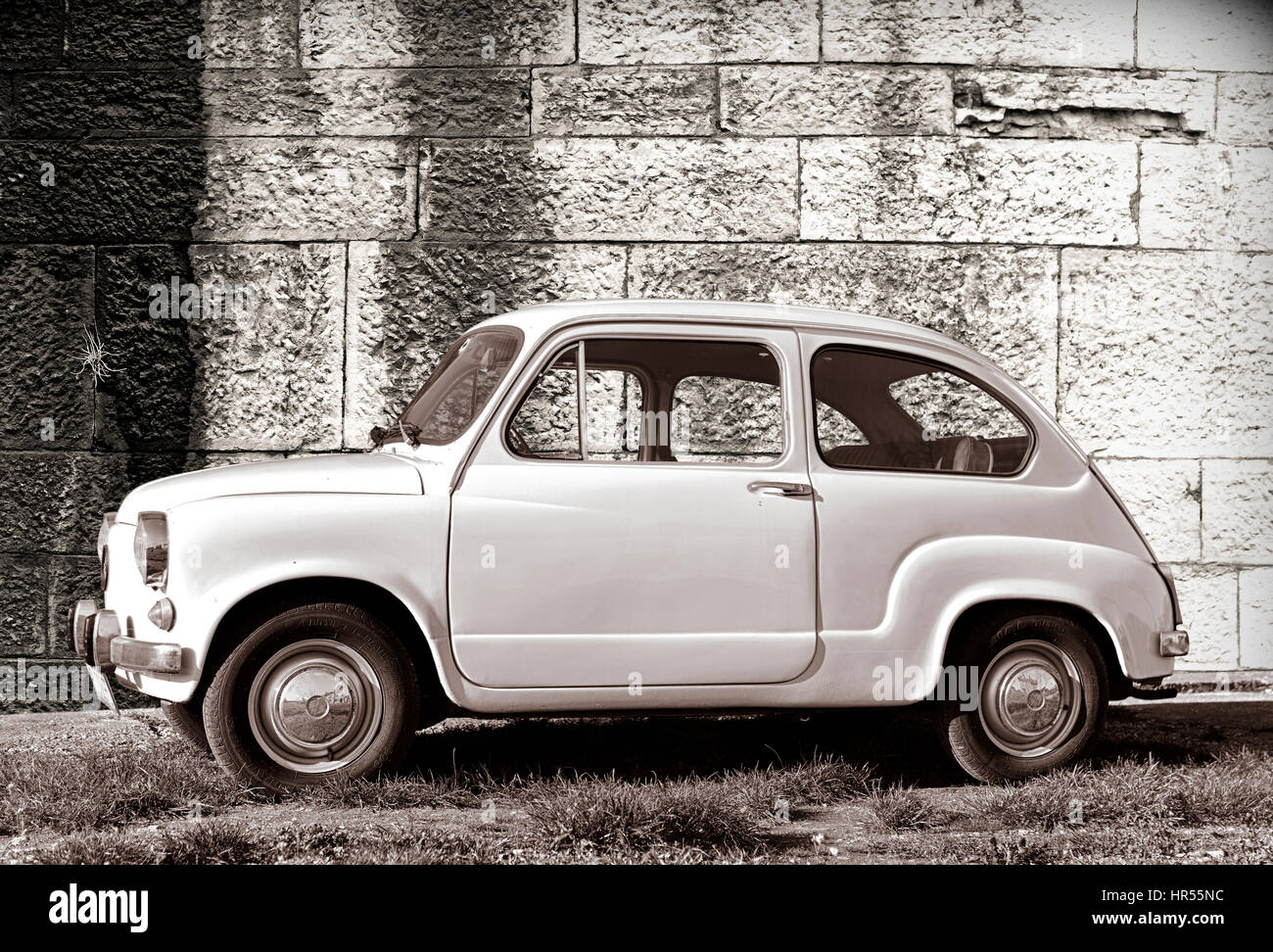 Weißen Oldtimer Super-mini-Auto, geparkt auf Rasen gegen alte Wand in Pula, Kroatien. Stockfoto