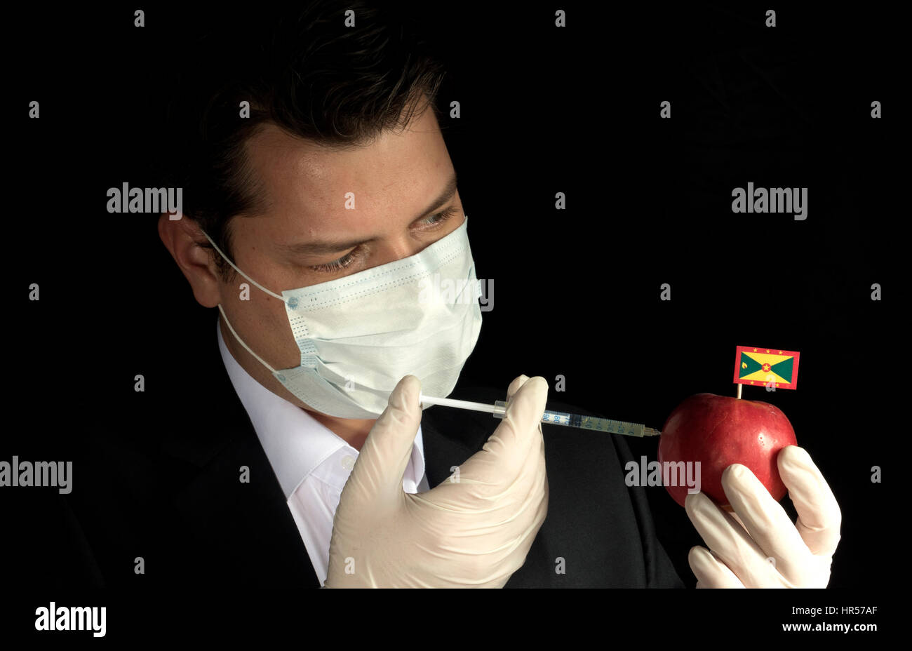 Jungunternehmer, die Injektion von Chemikalien in einen Apfel mit Grenada Flagge auf schwarzem Hintergrund Stockfoto