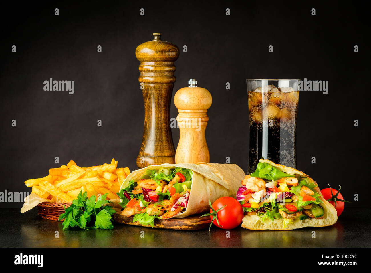 Fast-Food mit Döner Kebap, Döner, Pommes Frites und kalte Eis Cola mit Gewürzen und Gemüse Stockfoto