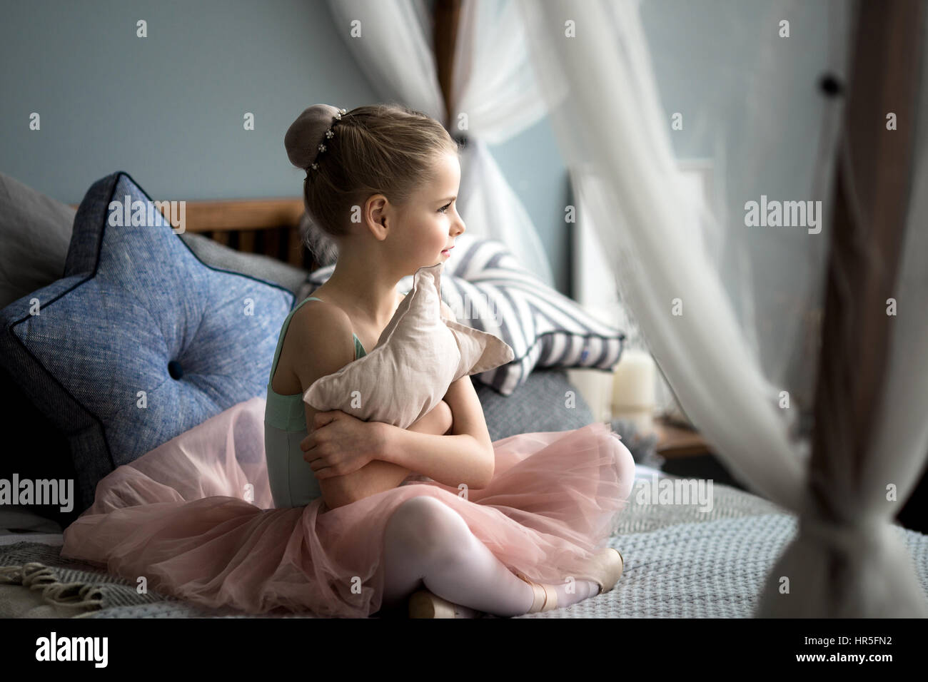 kleine Ballerina sitzt auf einem Bett Stockfoto