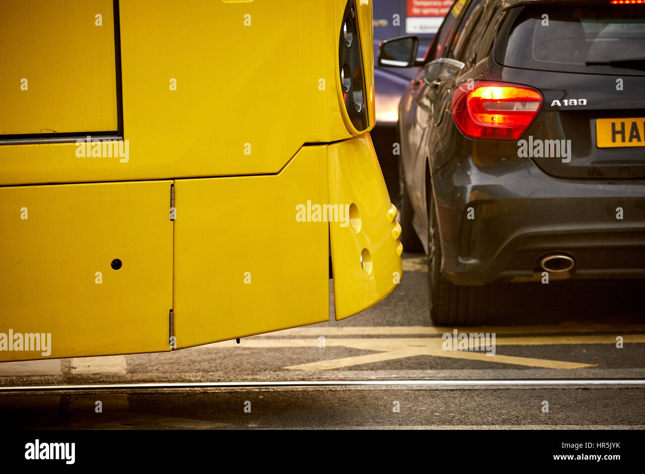 Eine gelbe Metrolink-Straßenbahn-Haltestelle mit Gewalt als ein Auto blockiert den Weg durch Parken auf einer Kastenverzweigung im Stadtzentrum von Manchester, England, UK. Stockfoto