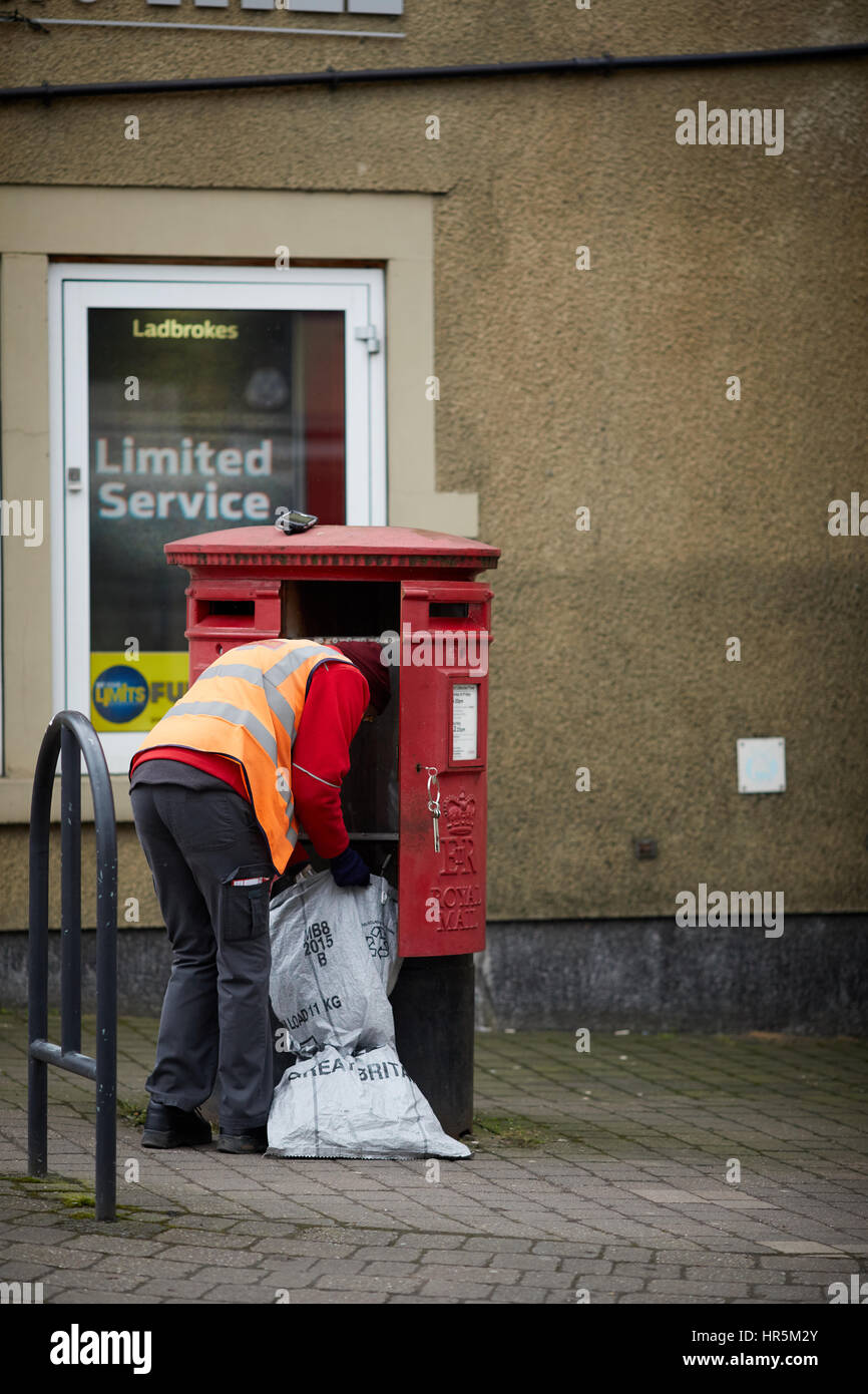 Postbote in Uniform Entleerung Briefe aus einen roten Royal Mail-Briefkasten am Hare Hill Road, Littleborough Dorf, Rochdale, Lancashire, England, UK. Stockfoto