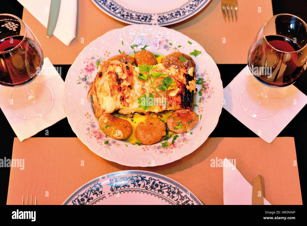 Gegrillter Kabeljau mit Kartoffeln auf einem vorbereiteten Tisch für zwei Stockfoto