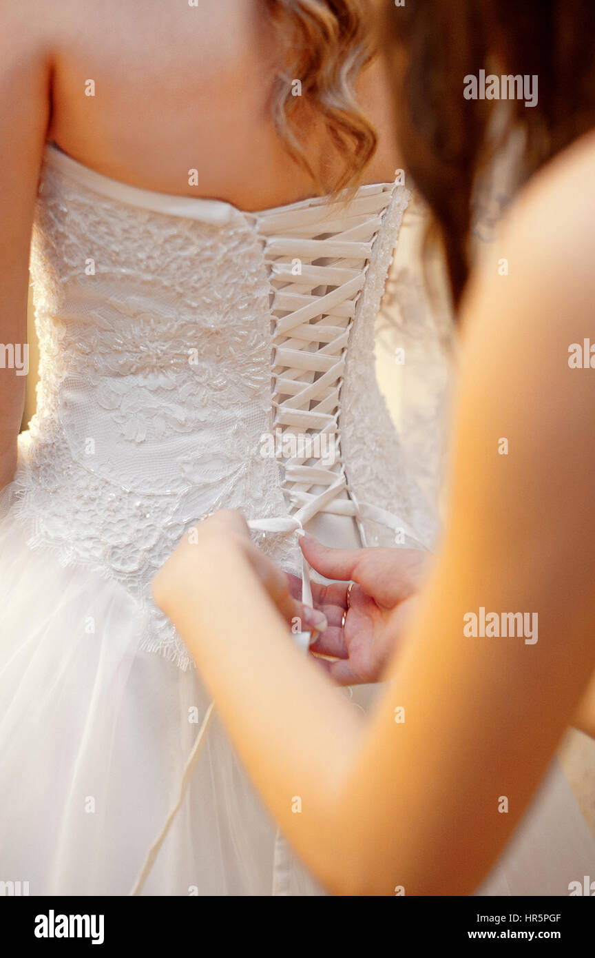 Brautjungfer hilft die Braut Kleid tragen. Stockfoto