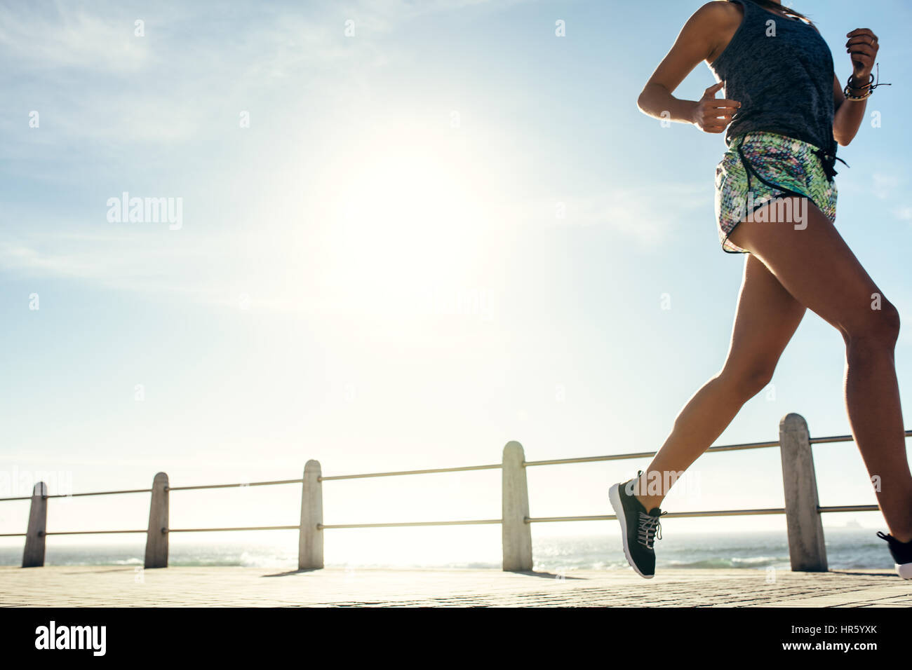 Schuss von Fitness-Frau läuft auf Meerseite beschnitten. Gesunde weibliche Läufer am Strand. Stockfoto