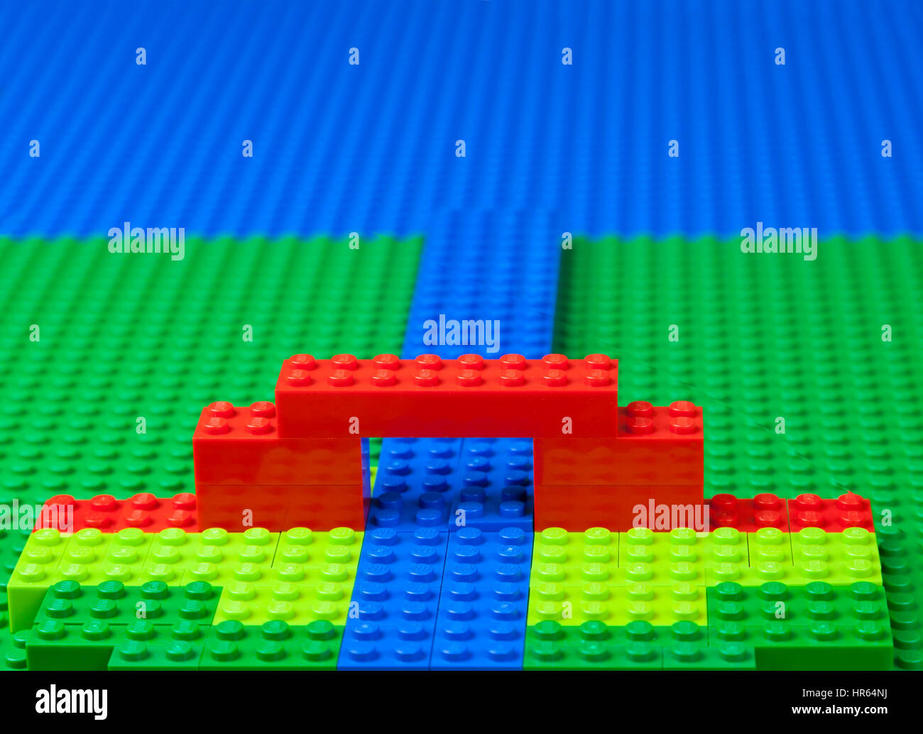 LEGO-Landschaft mit Brücke über Fluss, Strom, Kanal, etc. - grüne Wiesen oder Sumpfland und das blaue Meer. Stockfoto