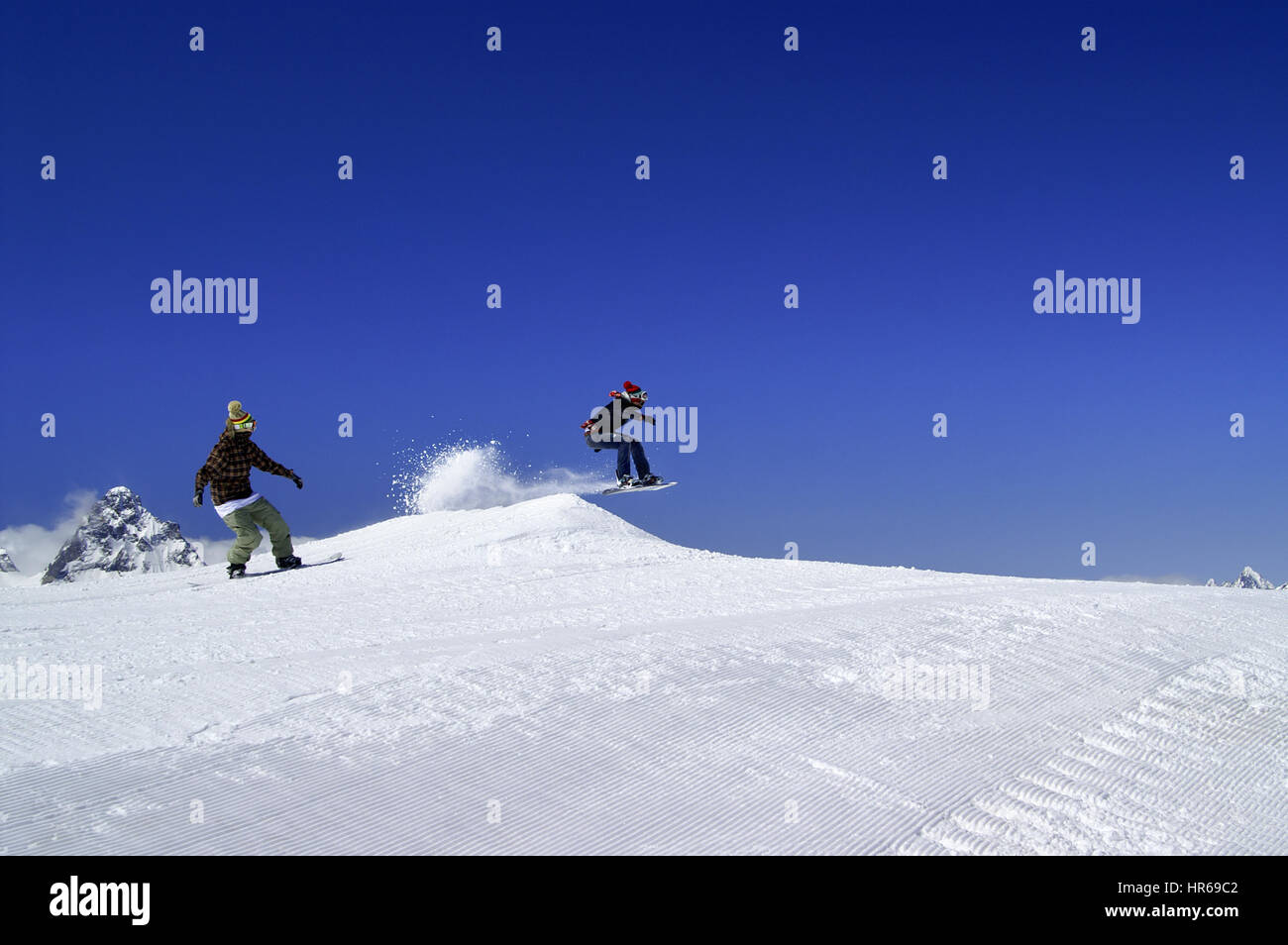 Zwei Snowboarder springen im Snowpark im Skigebiet an sonnigen Wintertag. Kaukasus-Gebirge, Region Dombay. Stockfoto