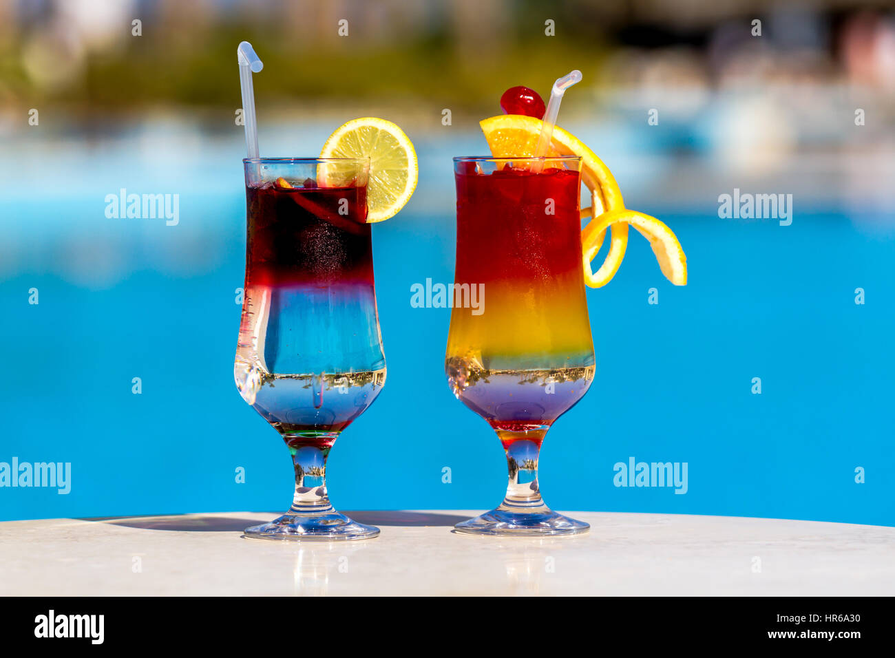 Schöne bunte Cocktails am Schwimmbad Hintergrund, Mädchen und Palmen Bäume Stockfoto