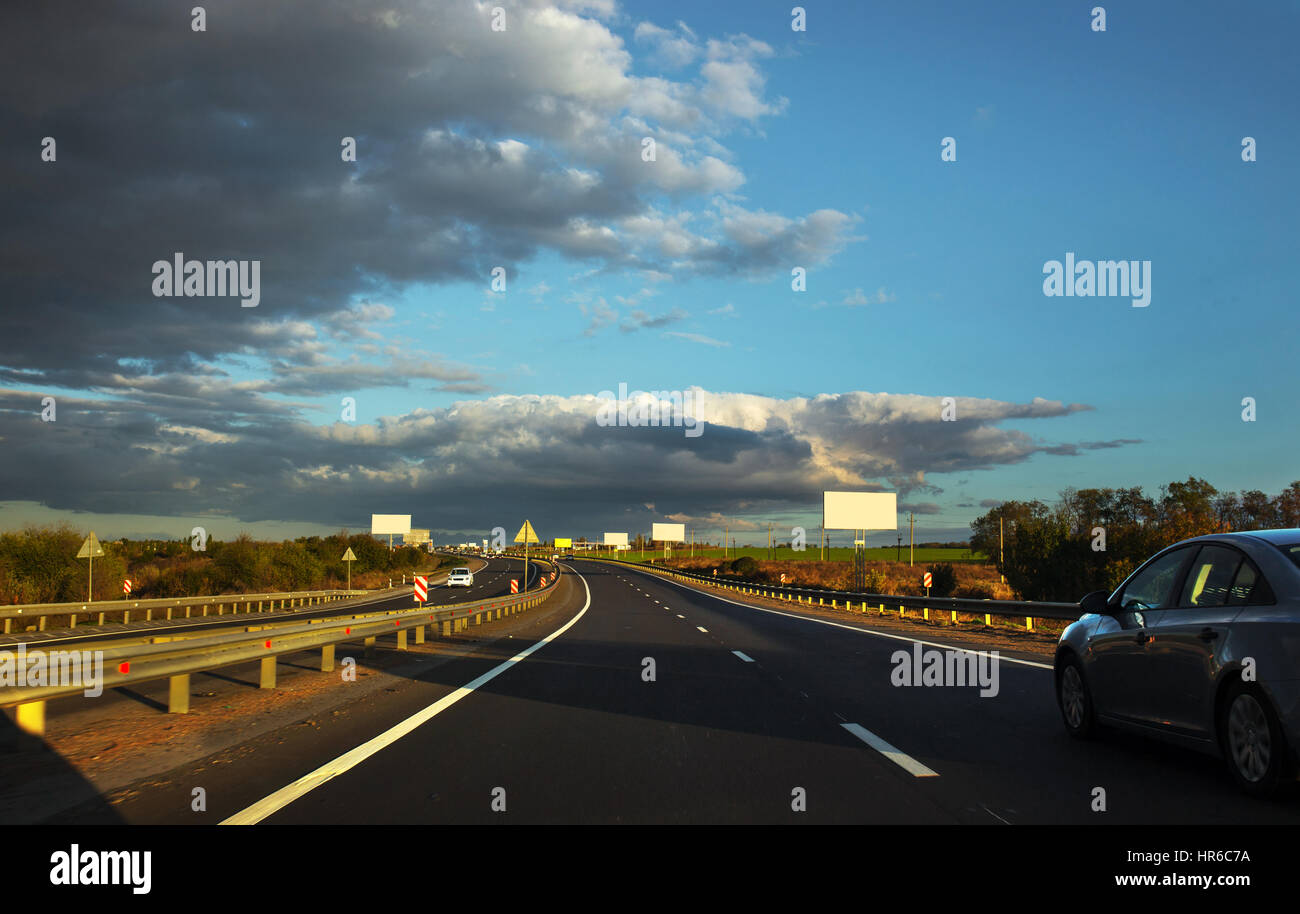 Zwei-Wege-Autobahn-Verkehr im Sonnenuntergang mit Autos. Stockfoto