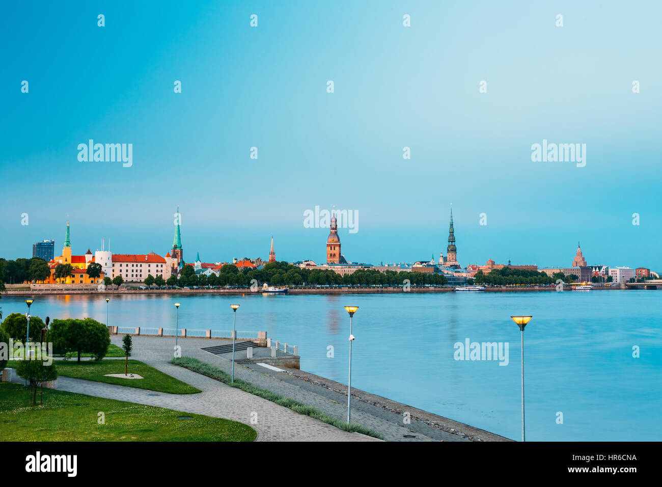 Malerische Aussicht, Promenad der Daugava In Riga, Lettland. Alte Kirche Türme und Burg im Hintergrund. Abend-Ansicht mit blauem Himmel. Reiseziel Stockfoto