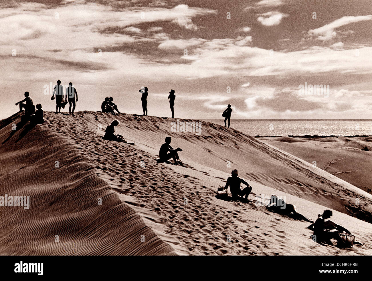 Gran Canaria MASPALOMAS DÜNEN RETRO URLAUB ENTSPANNUNG RUHE Zeitlos, gemäßigt, getöntes B&W Bild einer surrealen Anordnung von Menschen auf dem Kamm einer Sanddüne, in Maspalomas Gran Canaria Kanarische Inseln Spanien...Ian Shaw Kodak Fotograf Kodak 35 mm Art of 35 mm Fotobuch Stockfoto