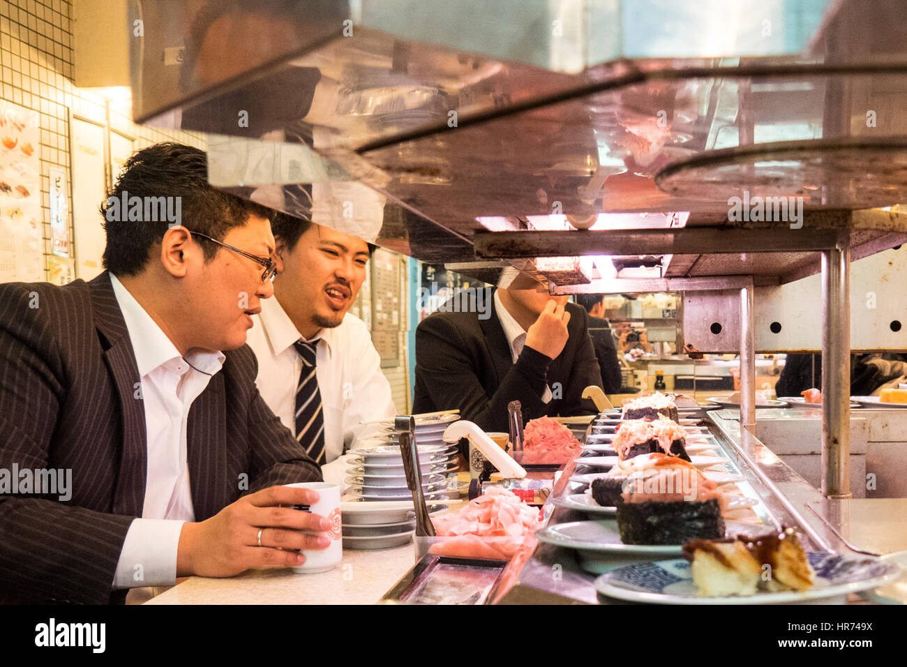 Ein Sushi-Restaurant, wo das Essen auf einem Sushi-Zug in Shinjuku, Tokio, Japan präsentiert wird. Stockfoto
