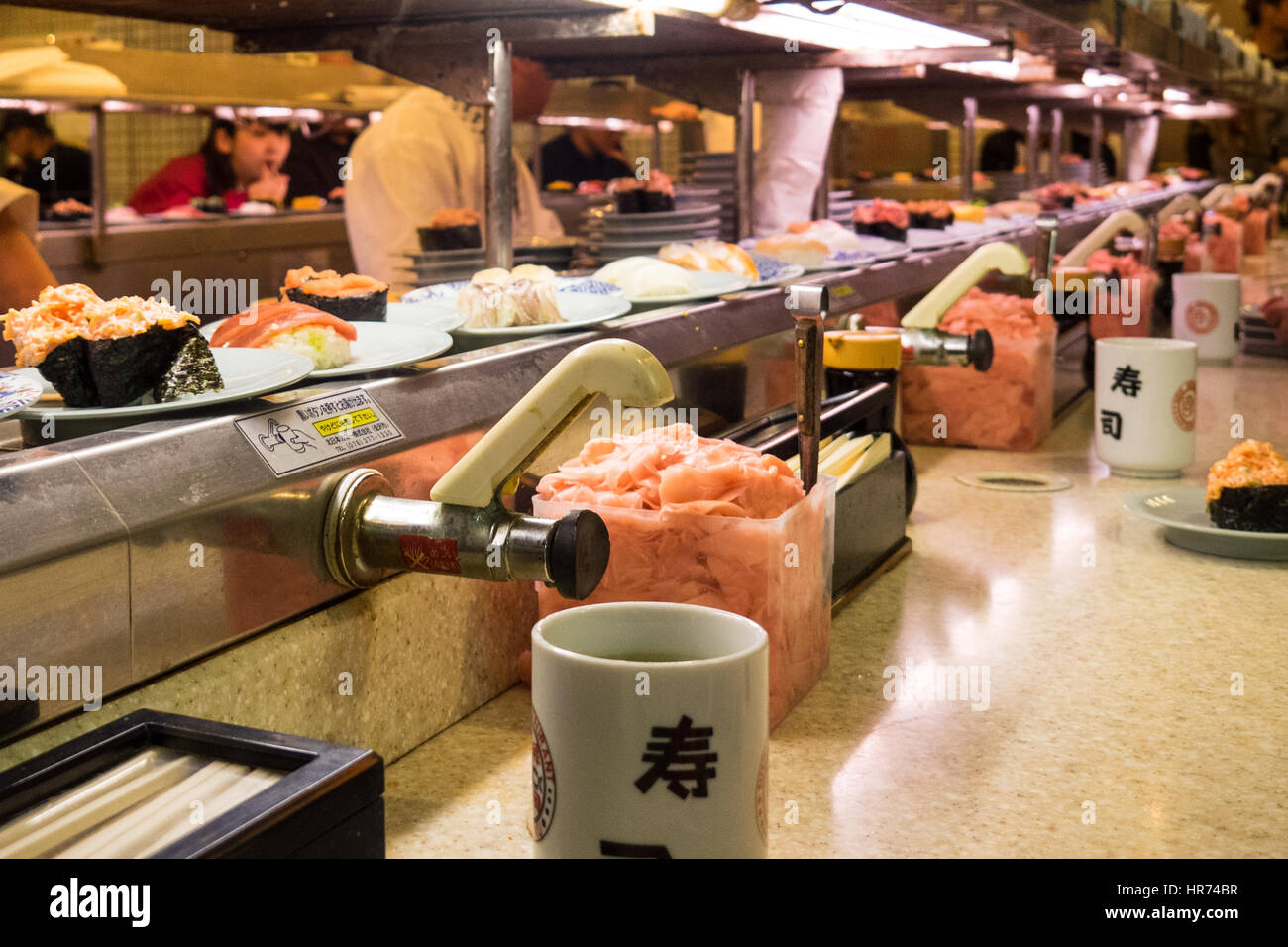 Ein Sushi-Restaurant, wo das Essen auf einem Sushi-Zug in Shinjuku, Tokio, Japan präsentiert wird. Stockfoto