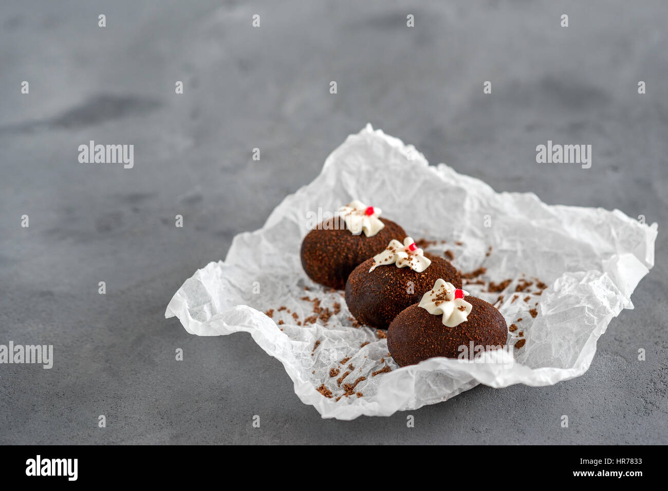 Kuchen aus Schokolade auf eine weiße Transparentpapier auf grauem Hintergrund. Kuchen mit rotem Gelee und zarte weiße Creme dekoriert. Stockfoto