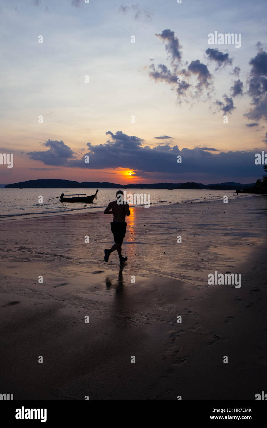 Ein Mann läuft am Ao Nang Beach bei Sonnenuntergang, Provinz Krabi, Thailand. Stockfoto