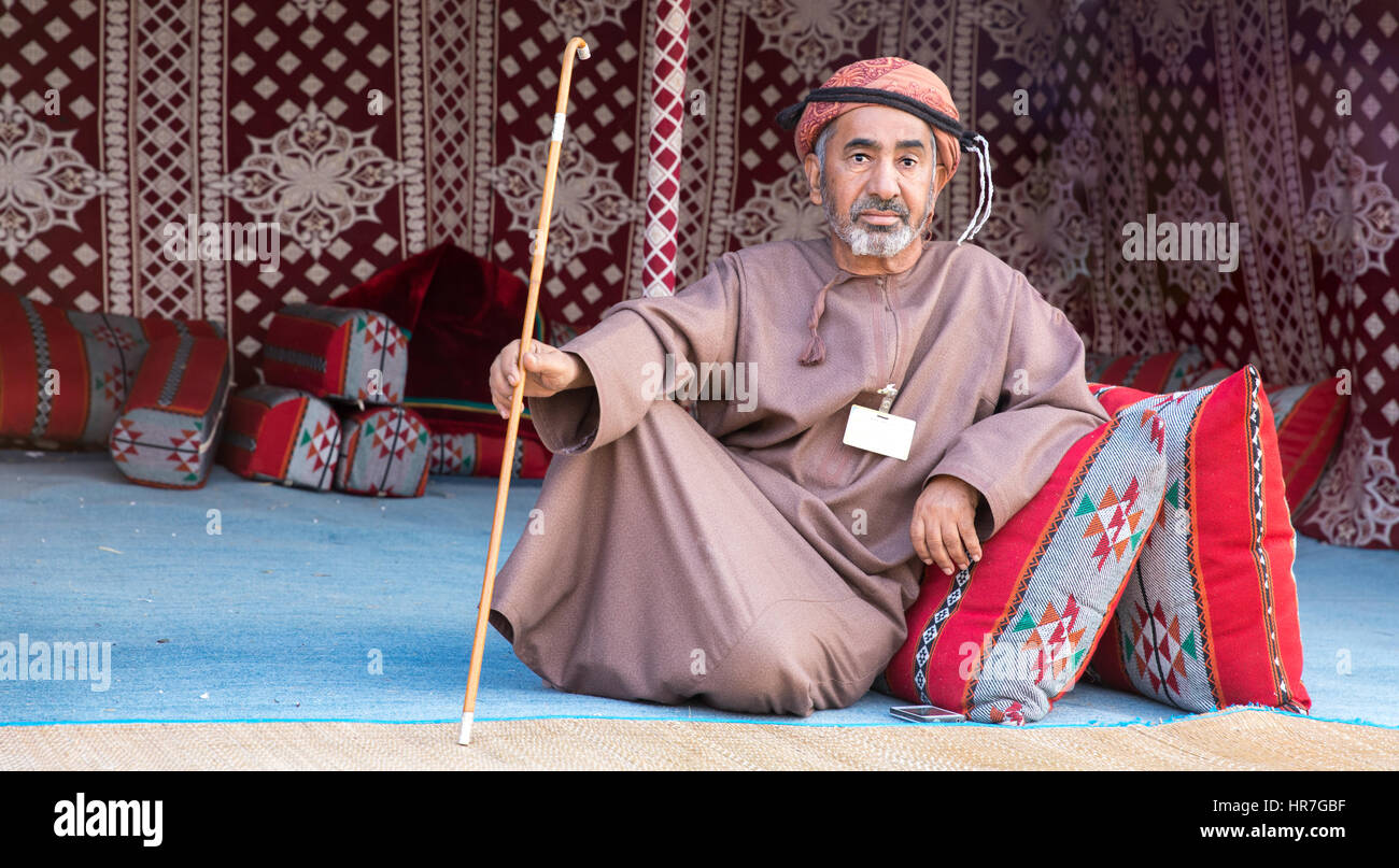 Muscat, Oman - 4. Februar 2017: Ein omanischen Greis in einem traditionellen omanischen Kleid lounging mit seinen traditionellen omanischen Stock. Stockfoto