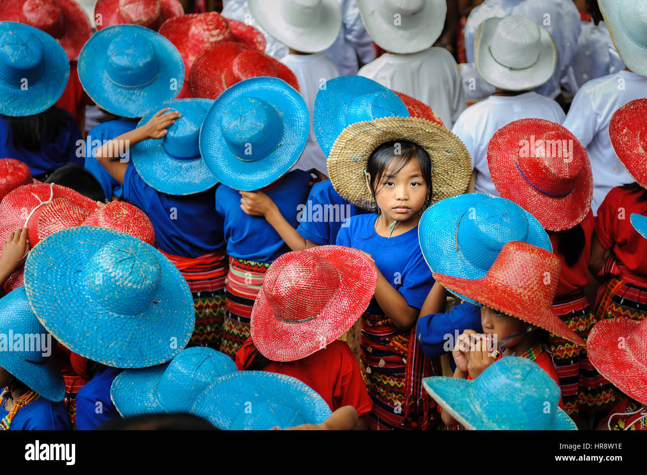 Ein Mädchen sucht die Kamera unter den vielen Kindern mit bunten hüten in einer Feier. Stockfoto