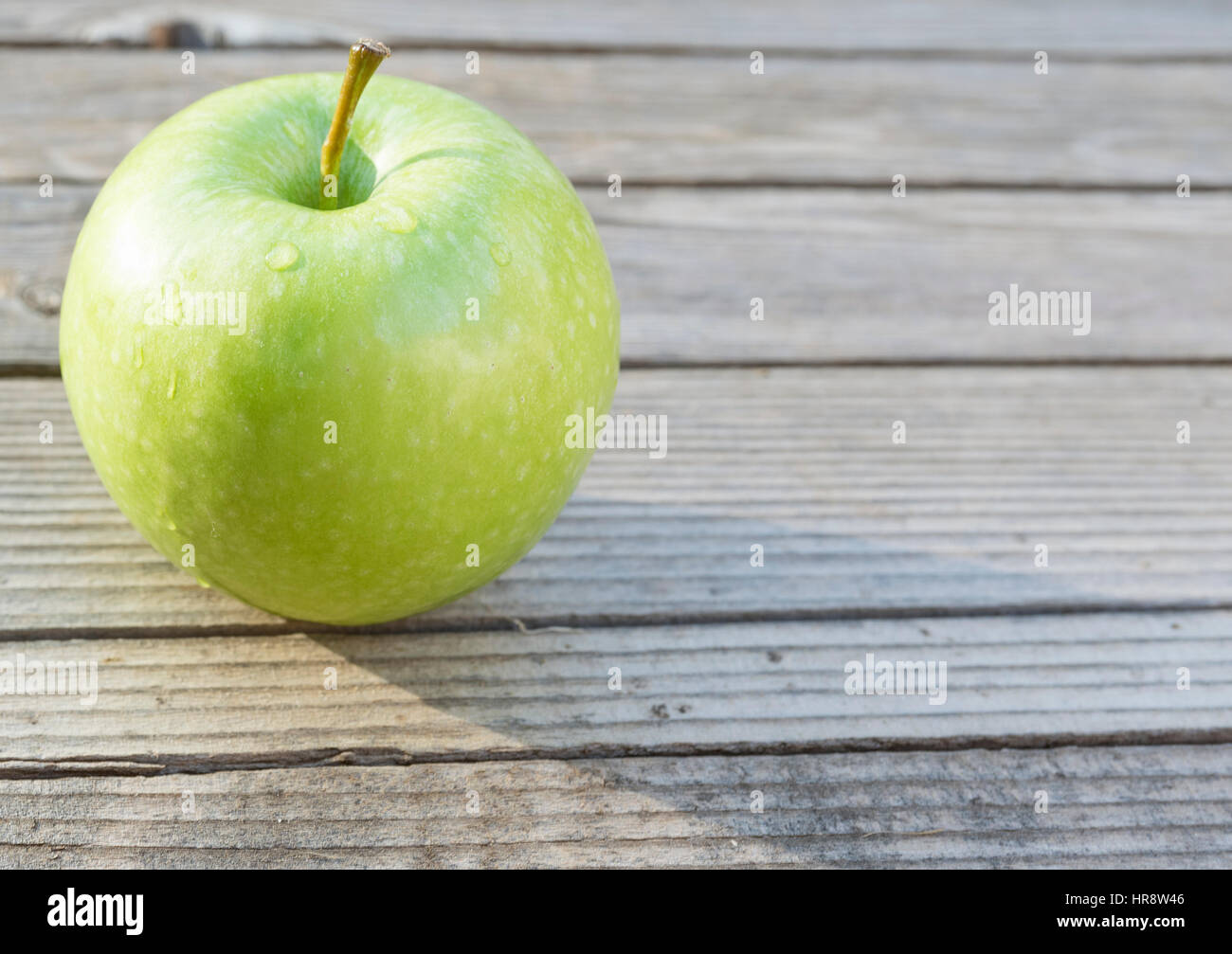 Eine grüne Bio Kochapfel auf einem hölzernen Hintergrund. Stockfoto