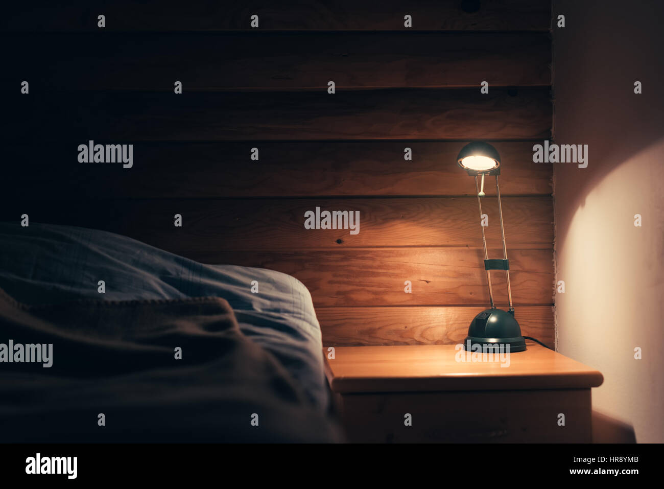 Schlafzimmer-Lampe auf einem Nachttisch neben einem schlafenden Bett Stockfoto