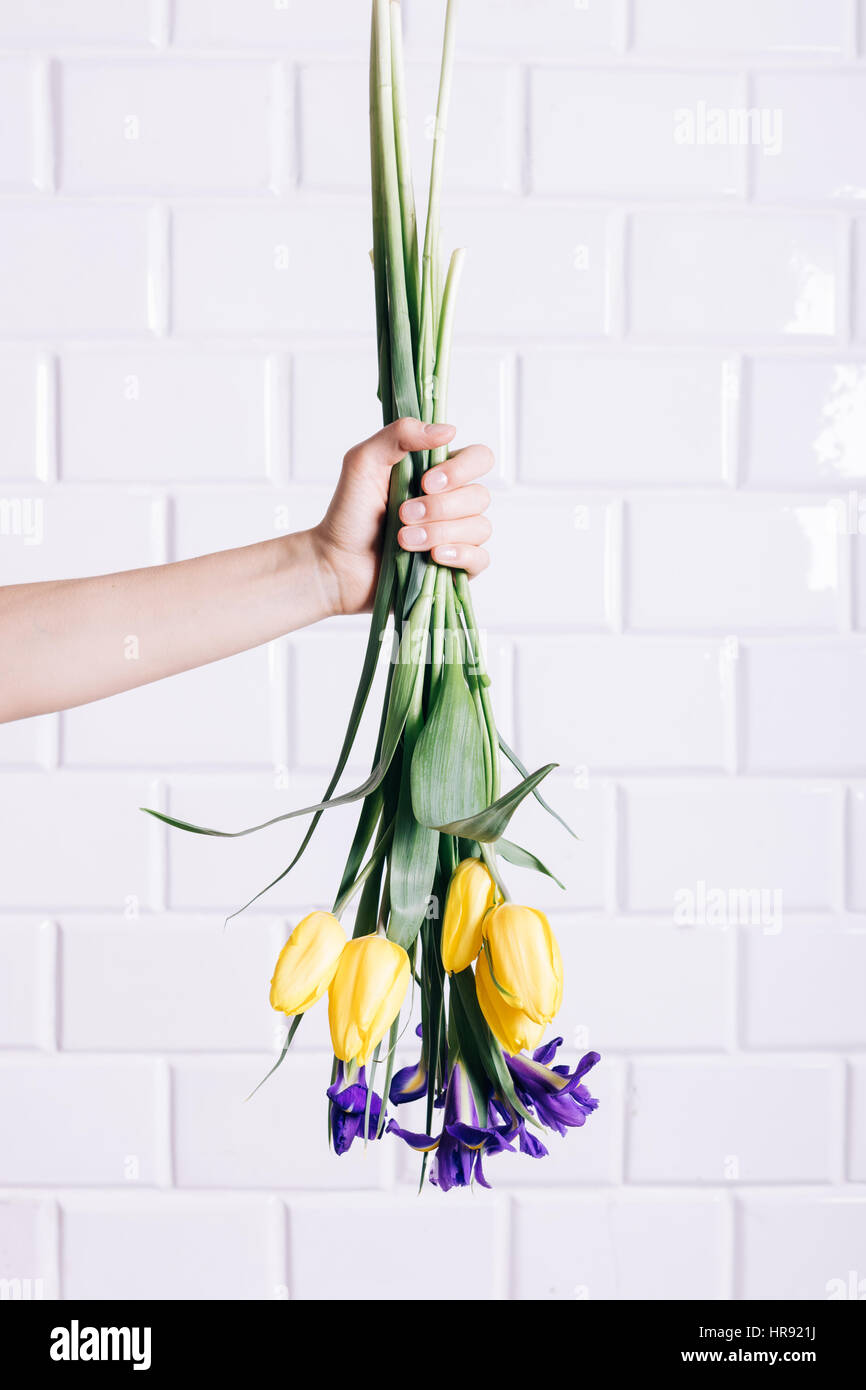 Weibliche Hand wirft ein Bouquet von gelben und violetten Blüten vertikale Rahmung Stockfoto