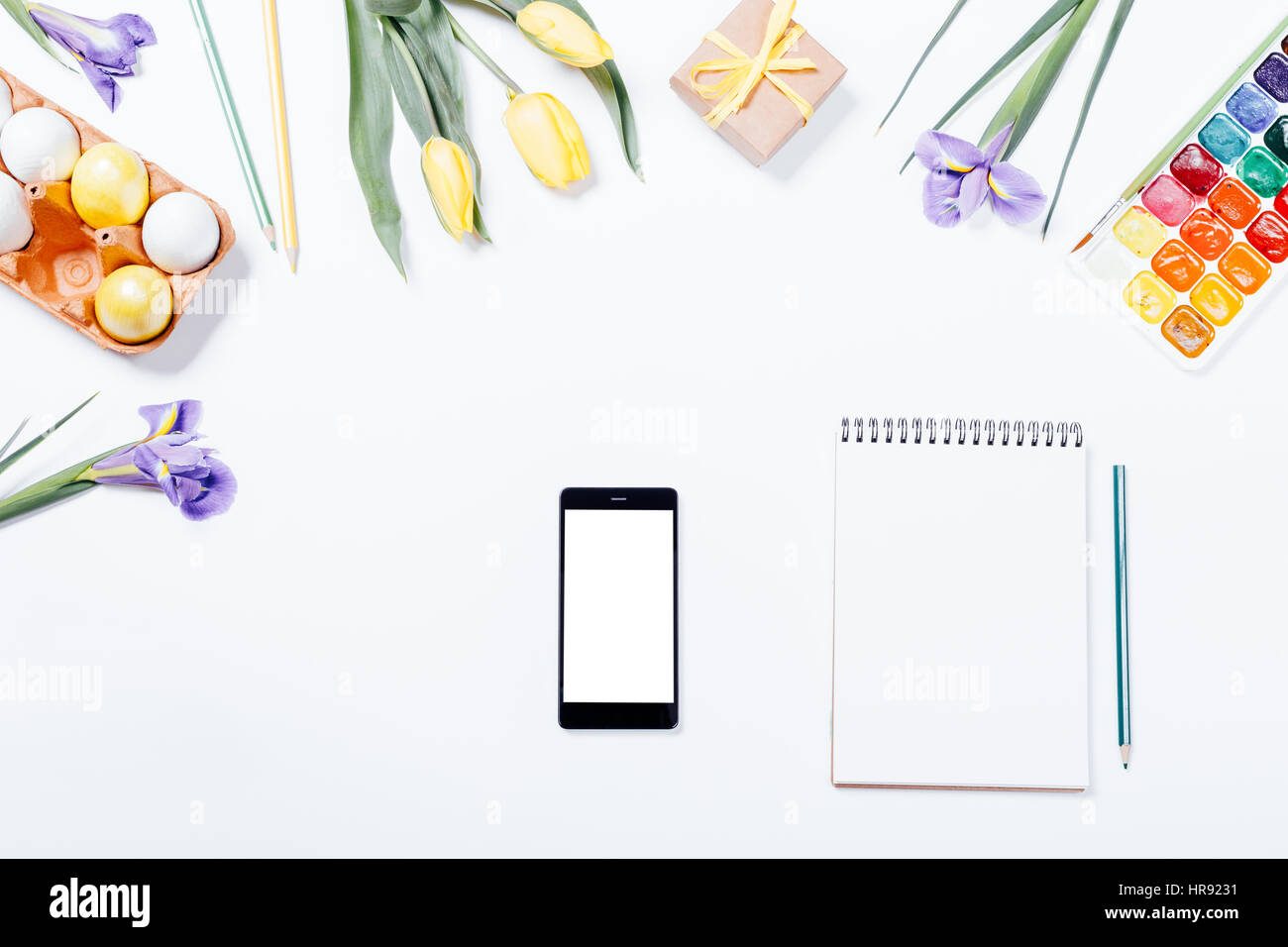 Ostern-Zusammensetzung: Blumen, Smartphone, bemalten Eiern, Aquarelle und Notebook. Ansicht von oben. Stockfoto