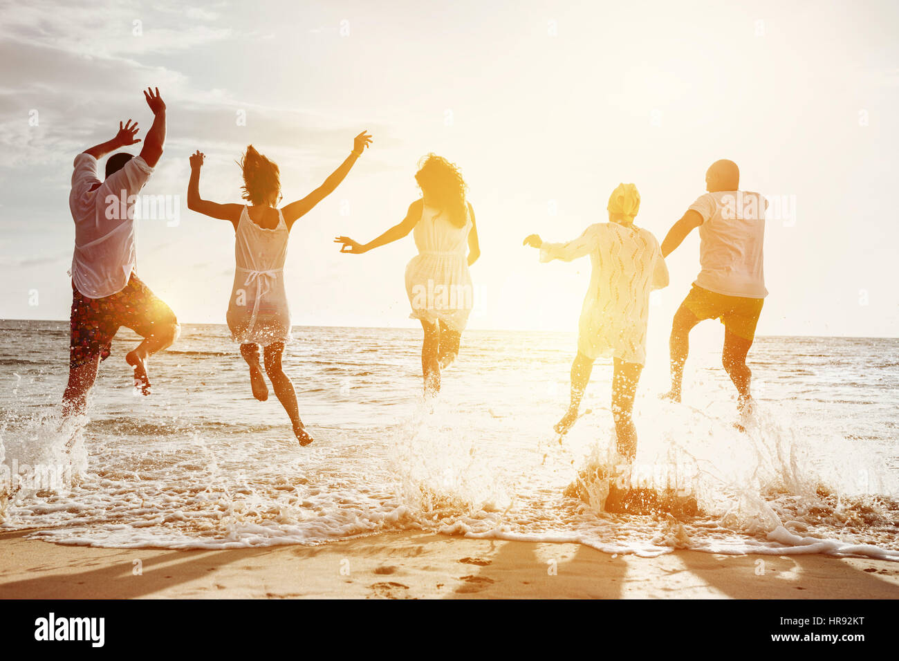 Glückliche Familie oder mit Freunden am Strand laufen und springen im Sonnenuntergang Meer. Freundschaft oder Ferien-Konzept Stockfoto