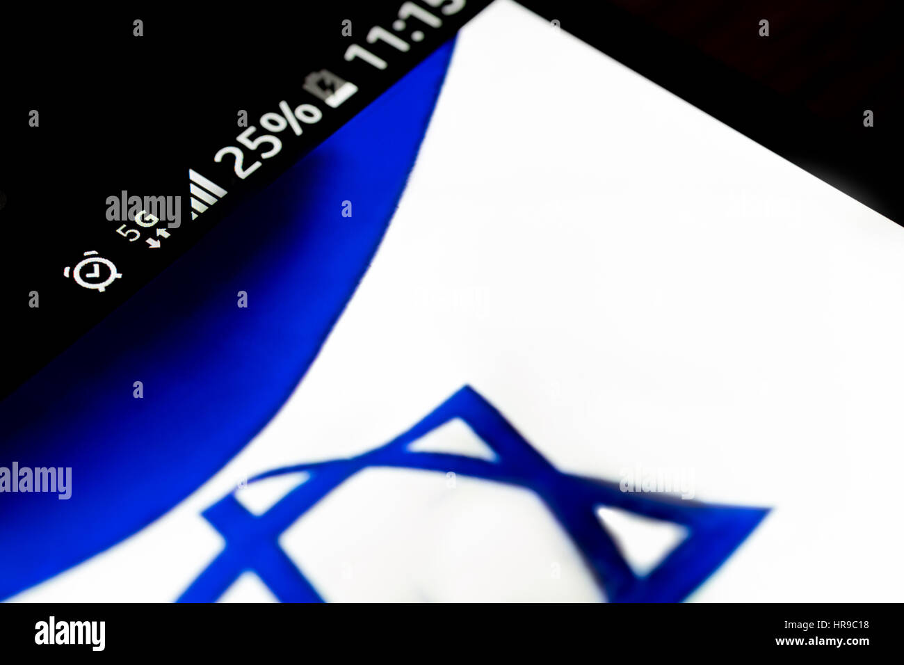 Smartphone auf hölzernen Hintergrund mit 5G Netzentgelt Zeichen 25 Prozent und Israel-Fahne auf dem Bildschirm. Stockfoto