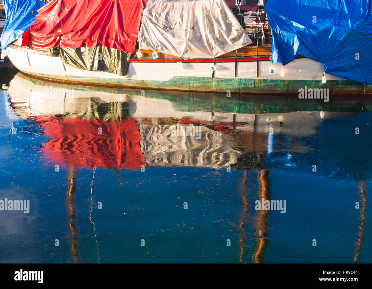 Bunte plane für ein Boot im Winterlager im Hafen von Oslo Norwegen, spiegelt sich in der eisigen Blau Fjord-Wasser Stockfoto